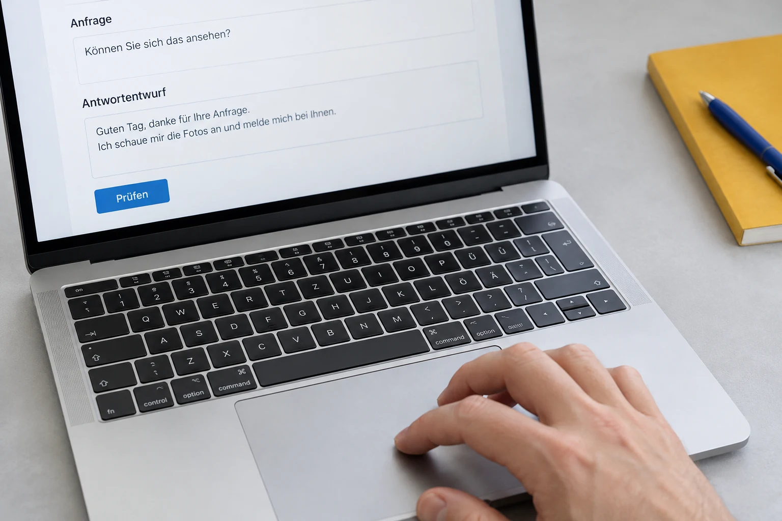 Eine Hand prüft einen Antwortentwurf am Laptop neben einem gelben Notizbuch.